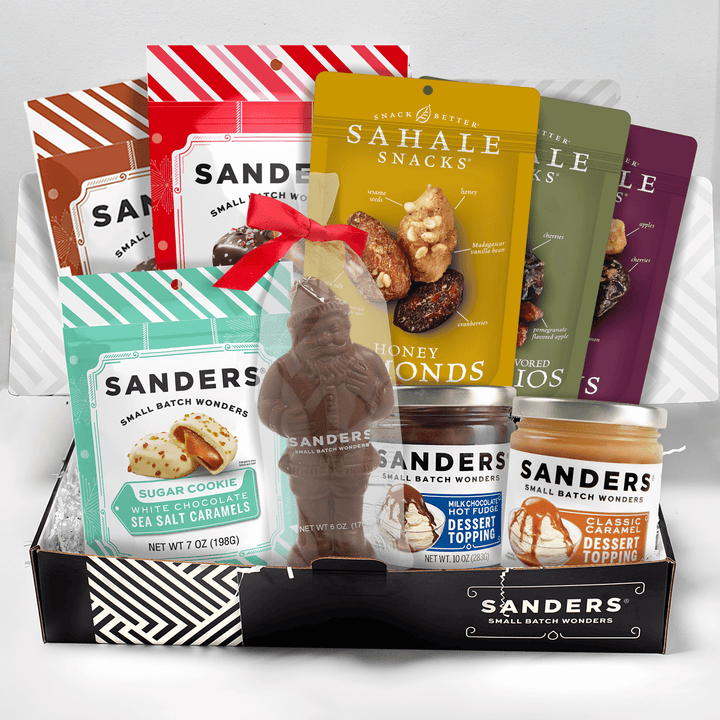 Assorted snack and candy items including Sahale Snacks and Sanders products in a box called Holiday Indulgence Gift Box