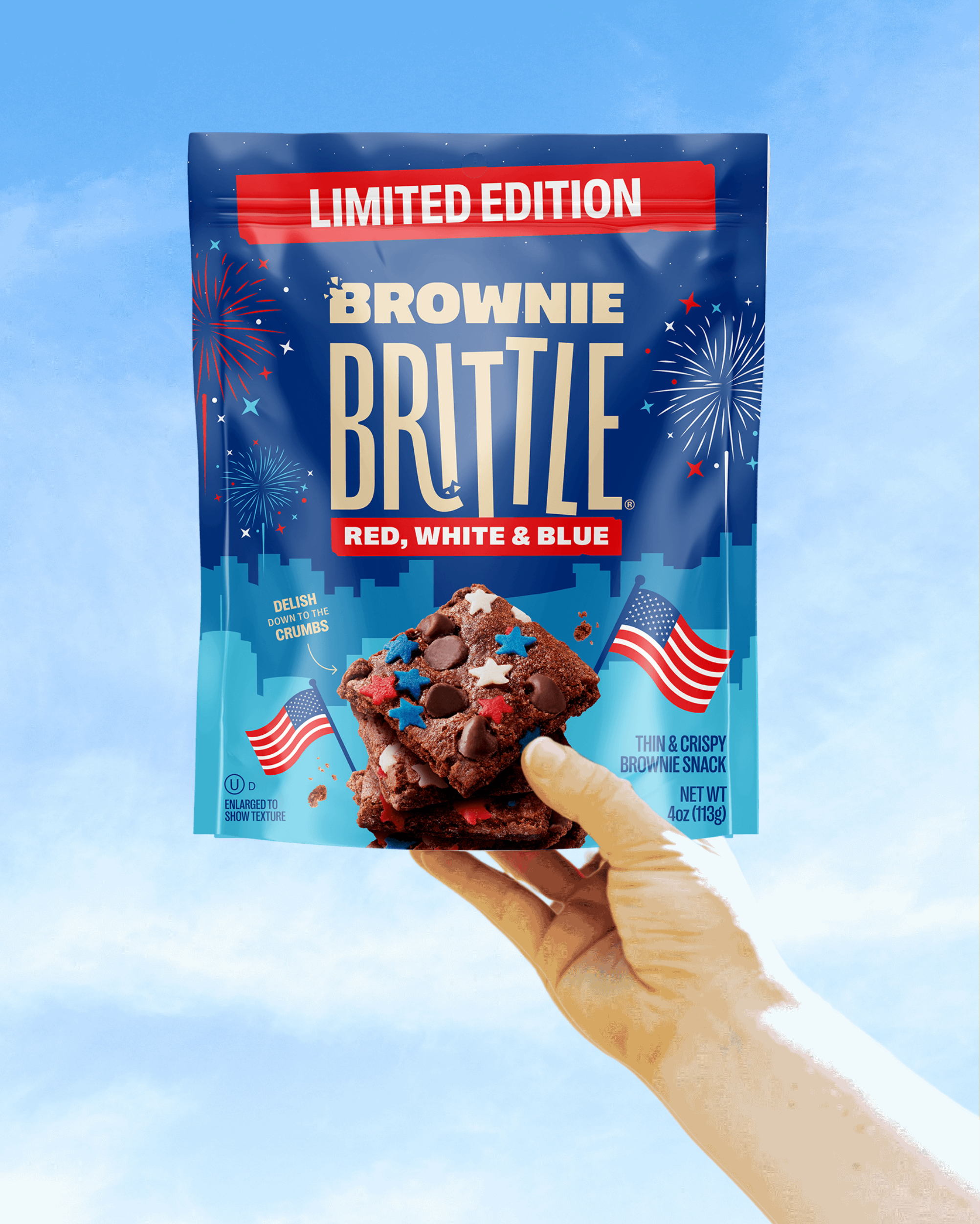 Hand holding a package of Brownie Brittle with a blue sky background