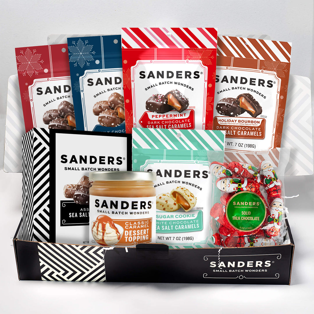 Collection of Sanders candy and dessert topping packages in a box on a white background