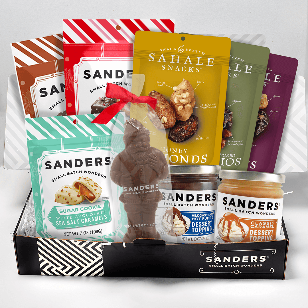 Assorted snack and candy items including Sahale Snacks and Sanders products in a box called Holiday Indulgence Gift Box